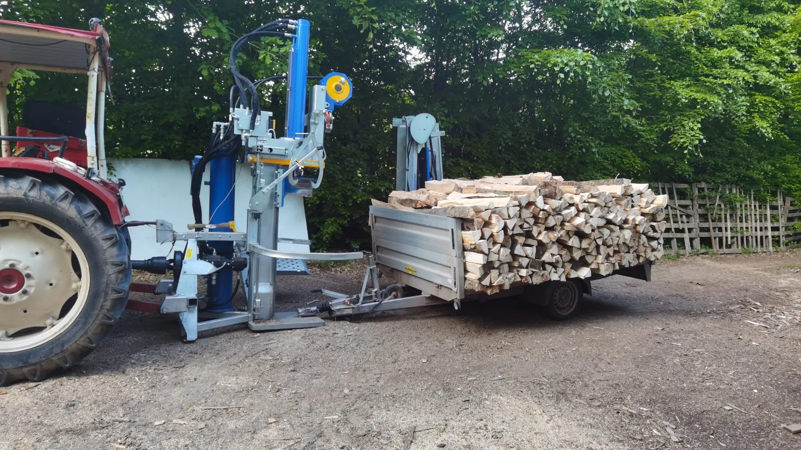 Traktor mit hydraulischem Holzspalter und beladenem Anhänger